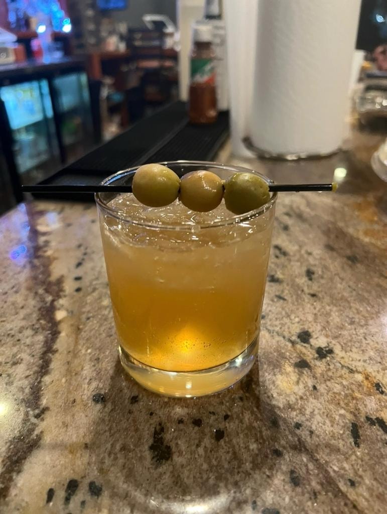 Amber cocktail on the rocks with olives at Downtown Cigar Company bar